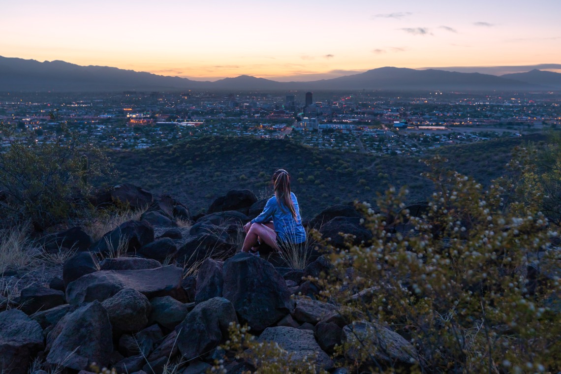 A woman in a blue shirt overlooking the city of Tucson on Tumamoc Hill 