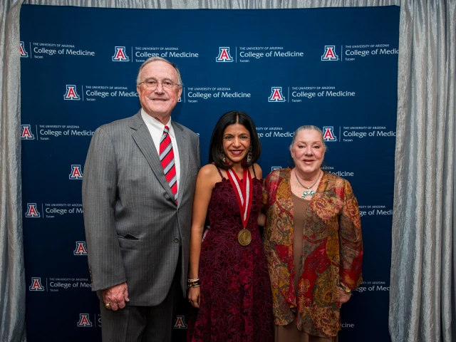 Three people standing in front of a "University of Arizona College of Medicine" backdrop