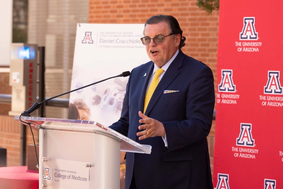A man addressing a group while speaking in front of a College of Medicine podium