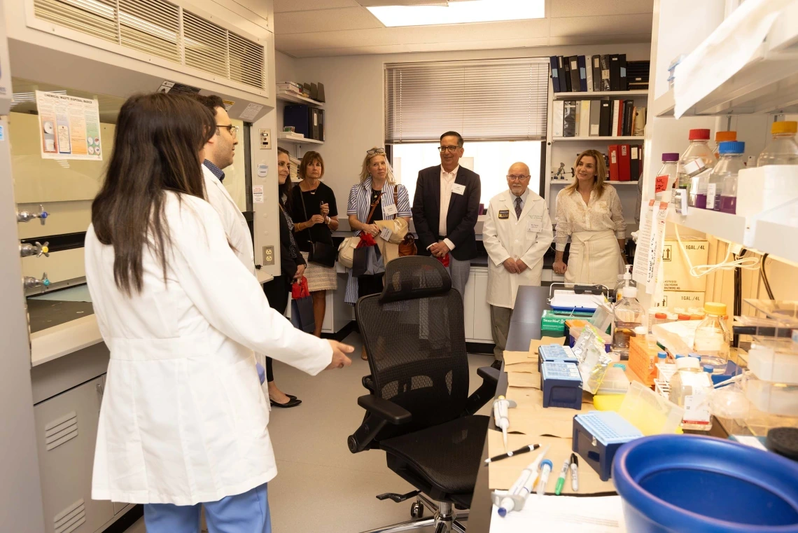 A group of people speaking to two researchers in a lab 