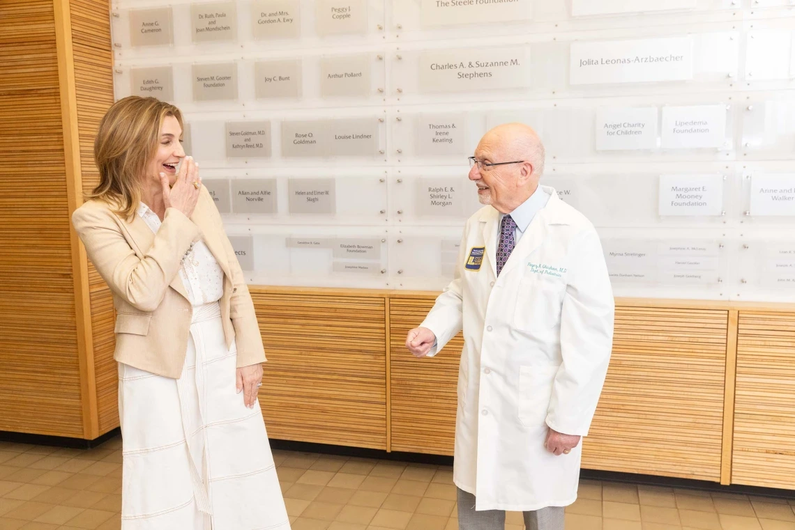 A woman wearing a white dress, smiling and talking to a man wearing a white coat. 