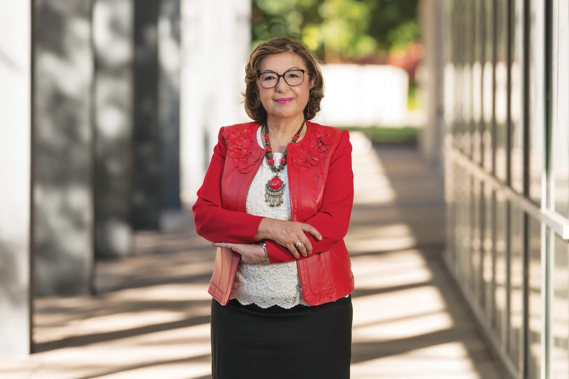 A woman smiling with her arms crossed, wearing a red jacket