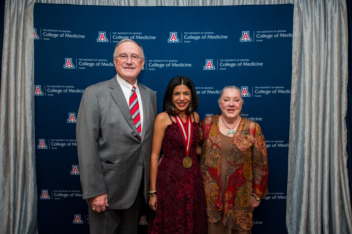 Three people standing in front of a "University of Arizona College of Medicine" backdrop