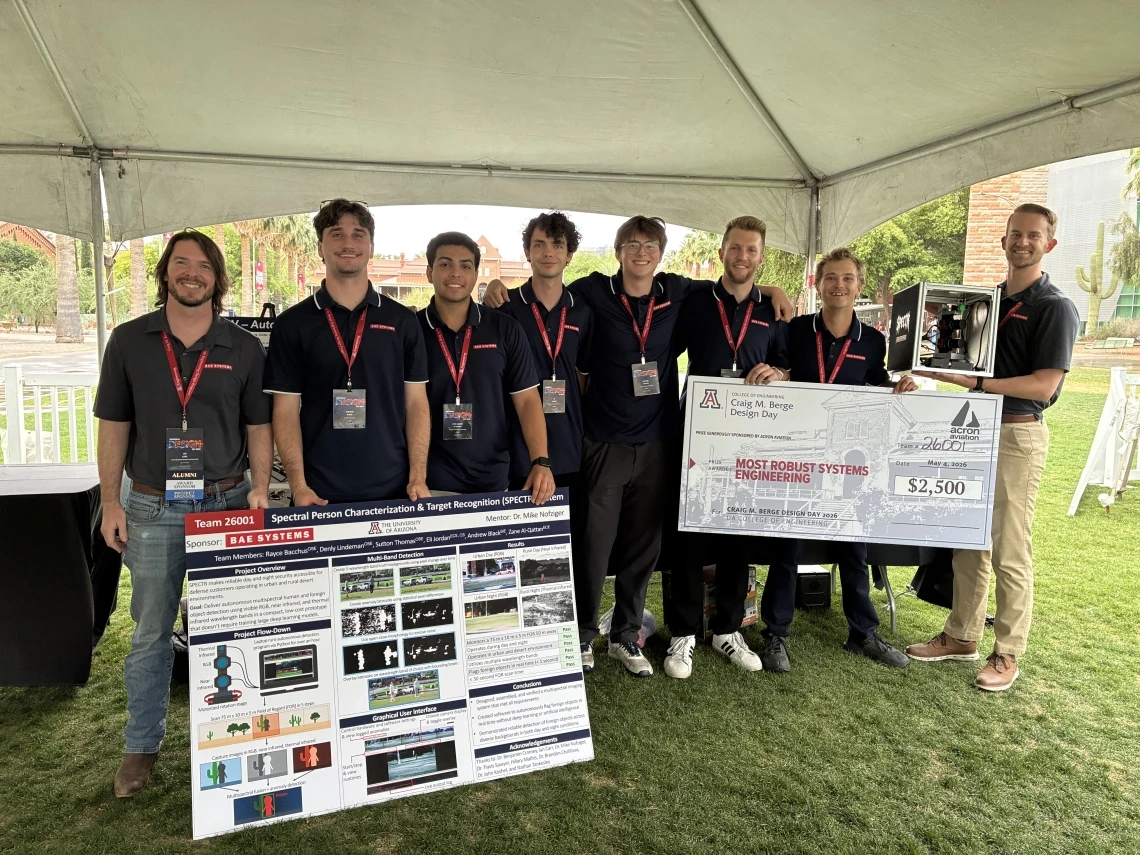University of Arizona engineering students pose with their senior design project display and a $2,500 Most Robust Systems Engineering award at an outdoor showcase.