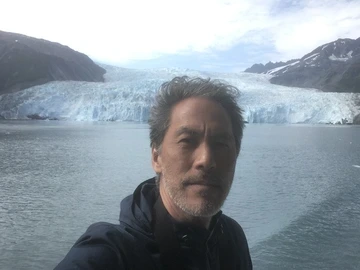A selfie of a man smiling in front of a body of water