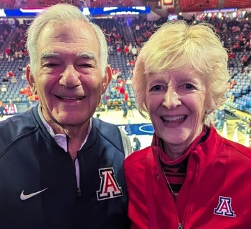Two Arizona fans standing and smiling at a basketball game