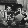 Two children wearing cowboy hats and boots, reading comics.