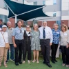A group of 11 people standing and smiling with their arms around each other at the W.A. Franke Honors College courtyard 